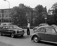 850411 Afbeelding van een verkeersagent die het verkeer regelt op de Catharijnesingel, bij de rotonde op het Ledig Erf, ...